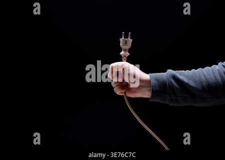 Hand holding cable with power connector Stock Photo