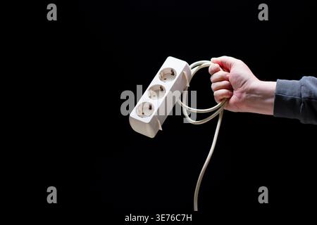 Hand holding power strip on black background Stock Photo
