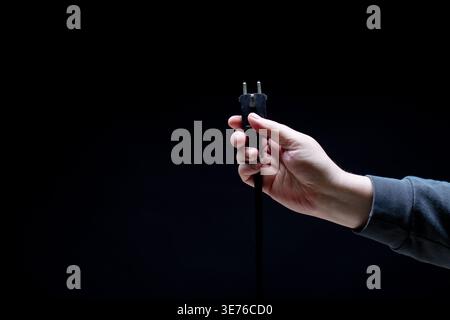 Hand holding black electric plug close up Stock Photo