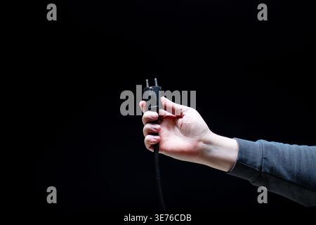 Hand holding black electric plug close up Stock Photo