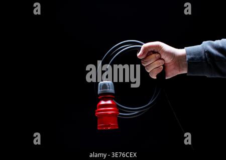 Hand holding red power connector on black background Stock Photo