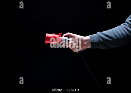 Hand holding red power connector on black background Stock Photo
