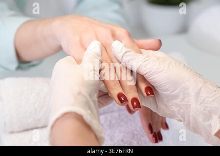 Professional manicurist applying cream on client's hands in beauty salon, closeup Stock Photo