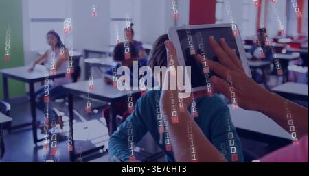 Holding tablet, teacher guiding seated teen boy at school classroom, showing binary overlay Stock Photo