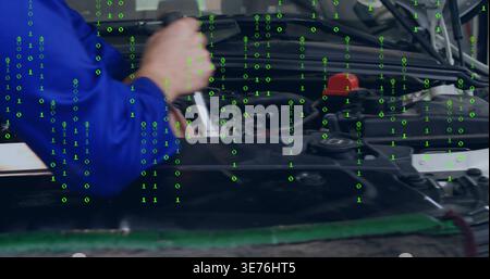 Reaching mechanic in blue coverall using wrench on engine bay at garage, showing red filler cap Stock Photo