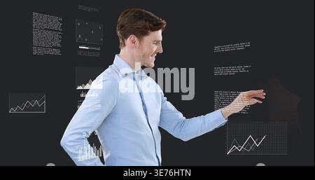 Reaching adult man manipulating holographic data charts in studio, wearing light blue dress shirt Stock Photo