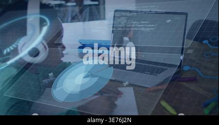 Writing child green-top leaning over paper with pencil at wooden table, laptop, HUD, copy space Stock Photo