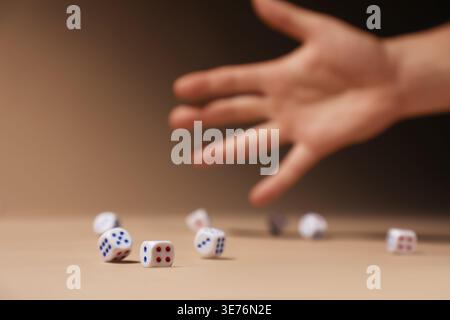 Male hand throwing game dices on beige background, closeup Stock Photo