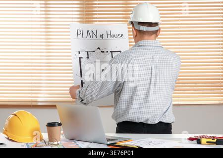 Male constructor working with house plan in office, back view Stock Photo