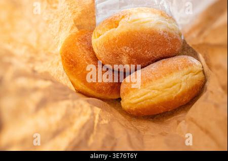 Freshly baked berliner donuts with powdered sugar in a brown paper craft bag, close up Stock Photo