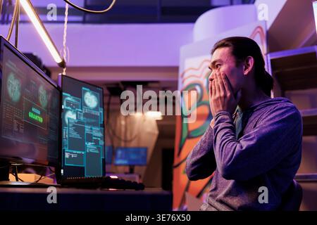 Excited hacker getting access granted while breaking into database server. Happy shocked young asian criminal hacking system successfully while doing illegal activities at night Stock Photo
