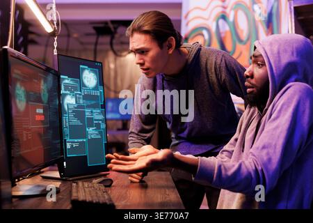 Disappointed hackers failing to break into server while looking at access denied message on computer screen. Angry unhappy criminals unsuccessfully hacking database cybersecurity system Stock Photo