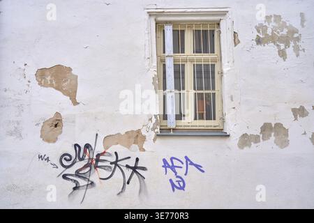 AFA anti-fascist action graffiti on old dilapidated house wall with barred window for security, house wall with graffiti and barred window, peeling pa Stock Photo
