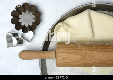 Rolled dough on cake tray with dough rollers and cookie cutters Stock Photo