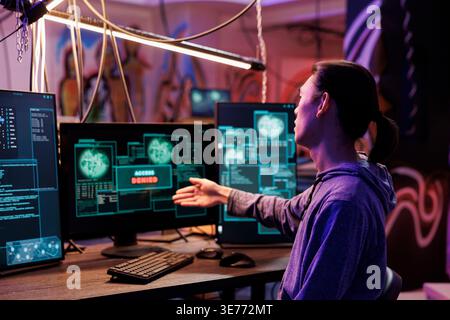 Disappointed hacker getting access denied while breaking website security system. Unhappy young criminal hacking online server unsuccessfully while doing illegal activity in abandoned warehouse Stock Photo