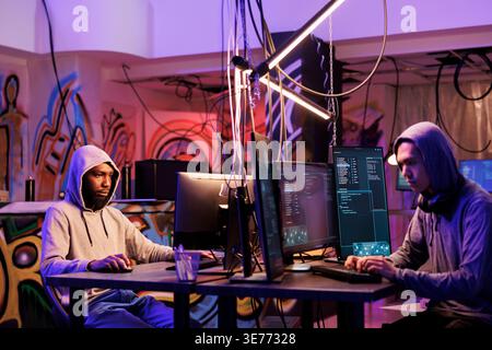 Two hackers using malware to break into system and steal information. Internet criminals coding illegal malicious software for cracking password and hacking computer network Stock Photo