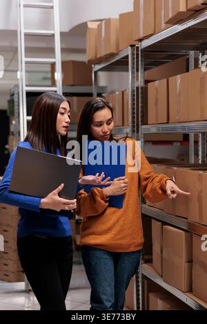 Warehouse managers checking goods maintenance in storage room. Storehouse asian women workers doing quality control operation and using inventory management software on laptop Stock Photo