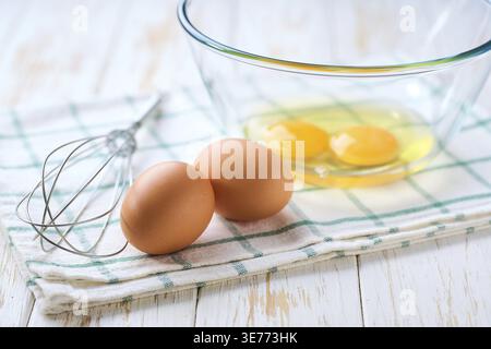 Cracked raw eggs on a light-colored kitchen table, selective focus. The process of omelette cooking Stock Photo