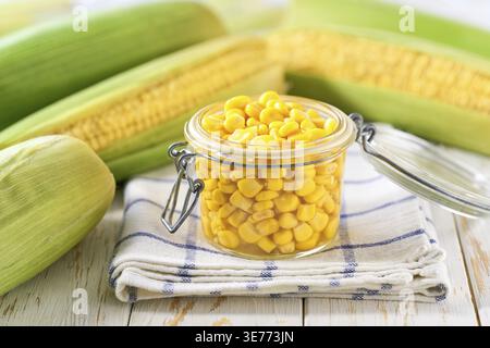 Canned sweet corn in jar on a white table, selective focus Stock Photo