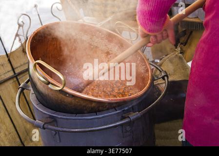Person roasting almonds in a metal kettle close-up street food Stock Photo