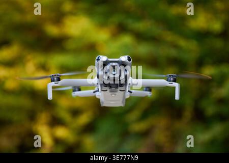Drone hovering in air in autumn park, quadcopter in flight with spinning propellers, close-up aerial technology and photography concept Stock Photo