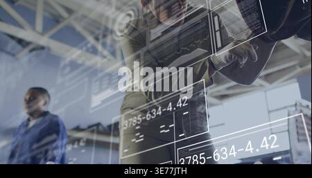 Diverse female coworkers wearing work gloves inspecting equipment prompted by HUD readouts in shop Stock Photo