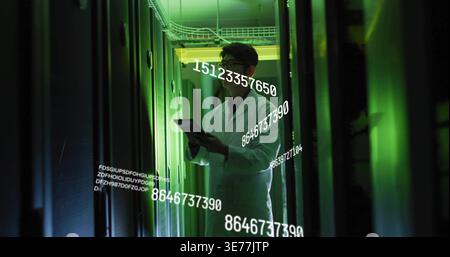 Inspecting Korean technician wearing white lab coat holding tablet in server aisle, numeric overlay Stock Photo