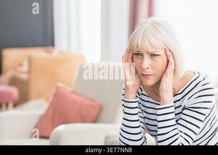 Woman suffering from headache, sitting at home Stock Photo