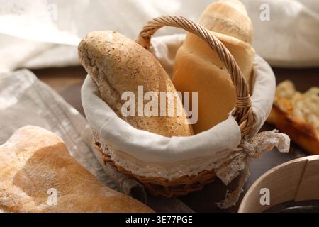 Assorted fresh bread rolls in wicker basket featuring whole grain and white wheat varieties. Close-up shot highlights healthy fiber-rich flour Stock Photo