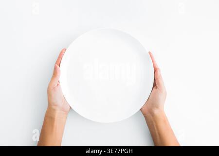 Female hands holding empty plate on white background Stock Photo