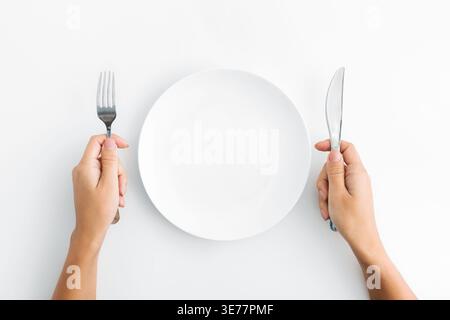 Whte plate with silver fork and knife on white background Stock Photo