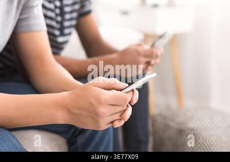 Two friends using smartphones while sitting on sofa Stock Photo