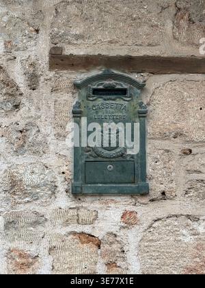 Vintage metal mailbox on rustic stone wall, suitable for backgrounds or historical themes. Mobile photo Stock Photo