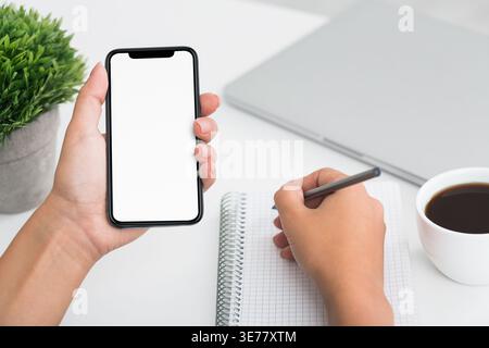 Fmale student hand writing on notebook and using smartphone Stock Photo