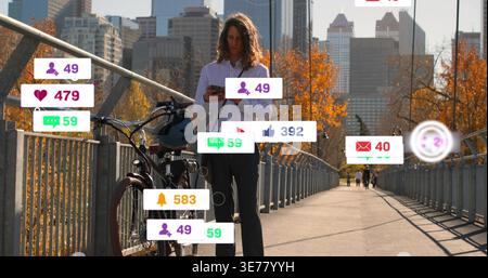 Standing man in white shirt checking phone on bridge, with bicycle, helmet, floating notifications Stock Photo