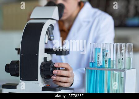 Close up of young adult woman adjusting microscope and examining samples in laboratory. Supporting medical research, diagnostics, biotechnology, or science education marketing Stock Photo