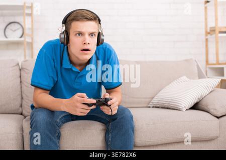 Teen guy playing video games with joystick Stock Photo