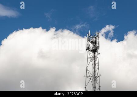 Bottom perspective pov of modern metal steel mobile 5g network wireless telecom tower against clear blue sky background on bright day. Microwave Stock Photo