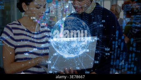 Analyzing colleagues wearing business-casual studying laptop in tech office, with holographic globe Stock Photo