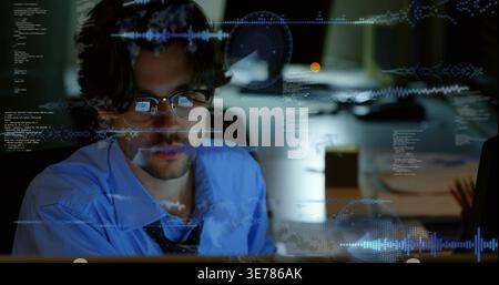 Man wearing blue dress shirt and loosened dark tie, studying code reflected in eyeglasses at desk Stock Photo