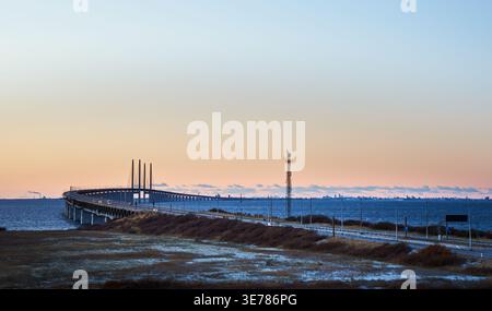 Sunset view from Lernacken of the Öresund Bridge curving over calm sea conveys infrastructure concept. Distant city of Copenhagen and coastal road Stock Photo