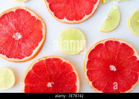 Freshly cut grapefruit slices isolated on a white background, bright pink or red citrus fruit pieces with juicy texture, healthy natural food concept. Stock Photo