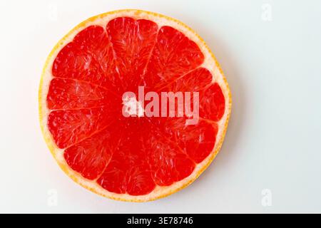 Freshly cut grapefruit slices isolated on a white background, bright pink or red citrus fruit pieces with juicy texture, healthy natural food concept. Stock Photo