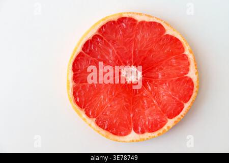 Freshly cut grapefruit slices isolated on a white background, bright pink or red citrus fruit pieces with juicy texture, healthy natural food concept. Stock Photo