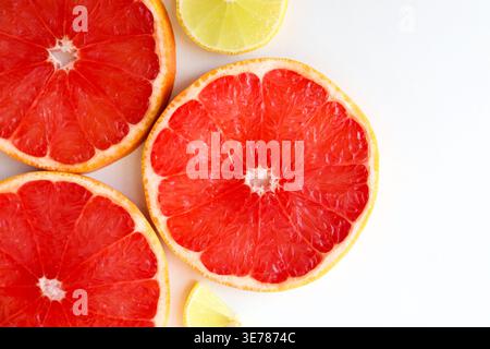 Freshly cut grapefruit slices isolated on a white background, bright pink or red citrus fruit pieces with juicy texture, healthy natural food concept. Stock Photo