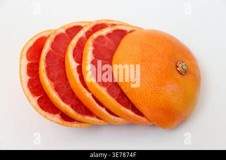 Freshly cut grapefruit slices isolated on a white background, bright pink or red citrus fruit pieces with juicy texture, healthy natural food concept. Stock Photo