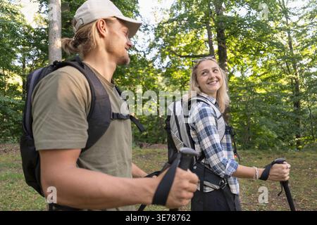 Smiling hikers talking together enjoying relaxed forest walk in nature Stock Photo