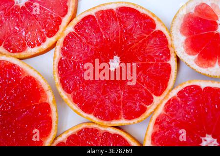 Freshly cut grapefruit slices isolated on a white background, bright pink or red citrus fruit pieces with juicy texture, healthy natural food concept. Stock Photo