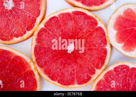 Freshly cut grapefruit slices isolated on a white background, bright pink or red citrus fruit pieces with juicy texture, healthy natural food concept. Stock Photo