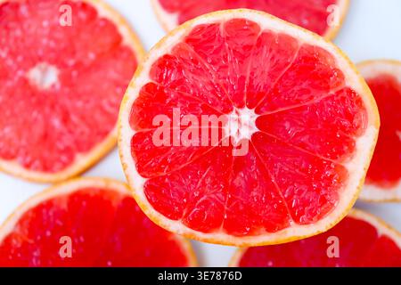 Freshly cut grapefruit slices isolated on a white background, bright pink or red citrus fruit pieces with juicy texture, healthy natural food concept. Stock Photo